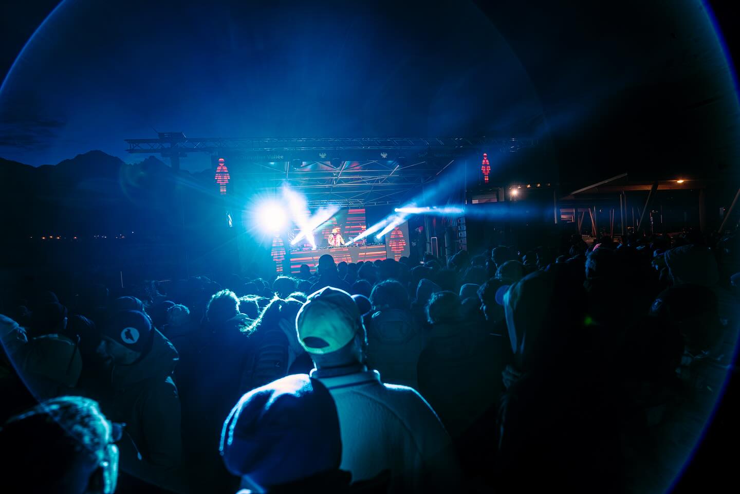 Public d’un concert de nuit au pied des pistes, sous les projecteurs bleus