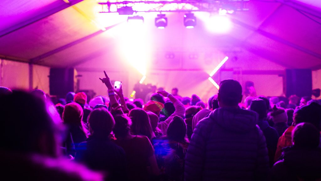 Public en fête sous les lumières roses d’un concert