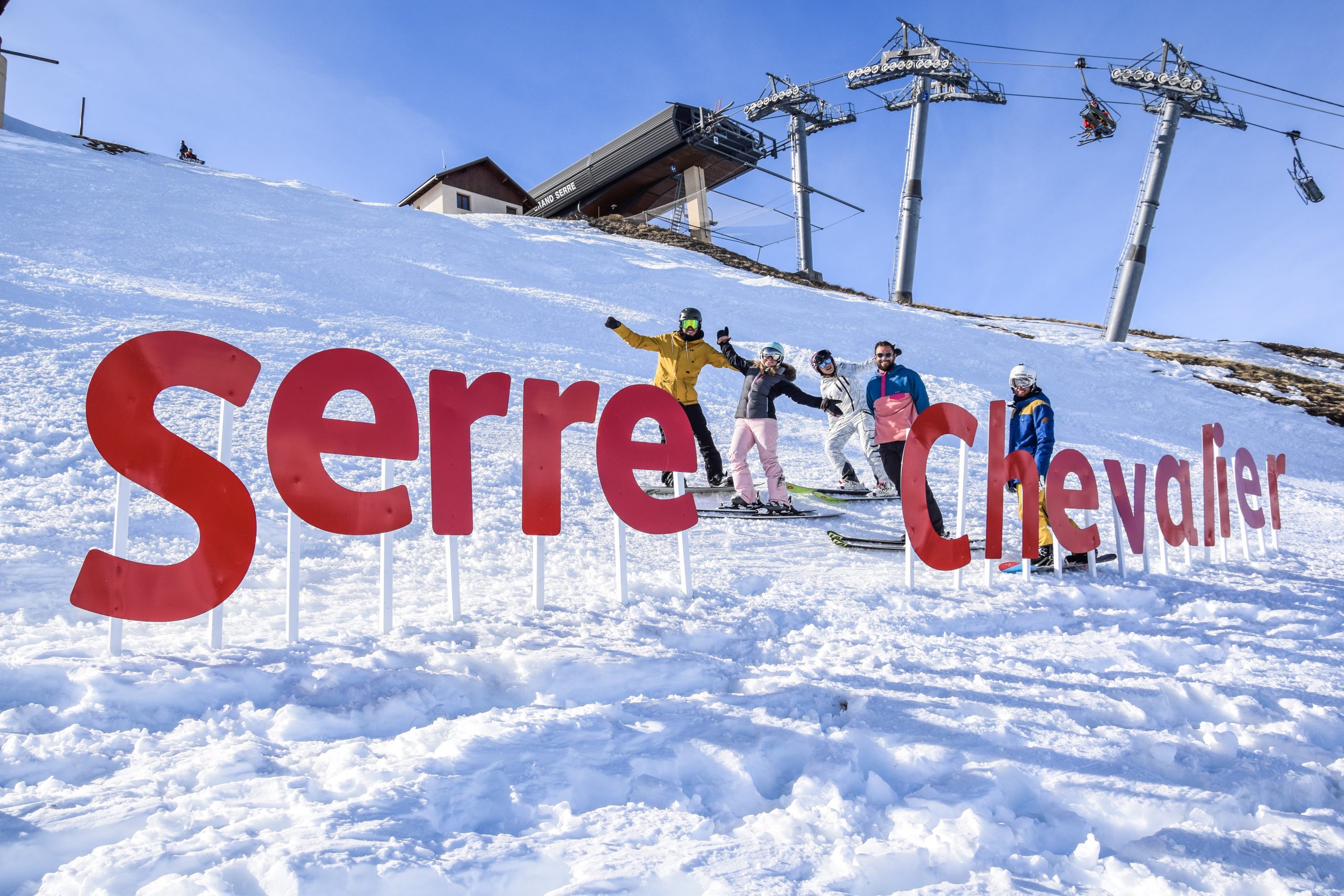 Skieurs devant les lettres géantes Serre Chevalier, sur les pistes